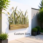 This image features a stylish outdoor garden setting with a decorative metal wall art piece mounted on a white wall. The wall art depicts a design of tall grass and delicate flowers, crafted from stainless steel, with a natural finish that highlights its intricate details. The metal flowers and grass are arranged to create a three-dimensional effect, casting subtle shadows on the wall behind. Below the wall art, a rustic wooden planter box adds a warm, natural touch to the display. The surrounding area includes lush green plants in black square pots placed on a tiled patio, with additional greenery and trees visible in the background. The scene is bathed in natural sunlight, emphasizing the modern yet organic aesthetic. There is a label reading "Custom Size" indicating that the wall art can be customized to fit different outdoor spaces. Overall, the setting combines artistic metalwork with natural elements to create a peaceful and inviting garden atmosphere.