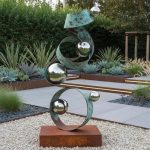 corten steel and vedigris sculpture in modern garden
