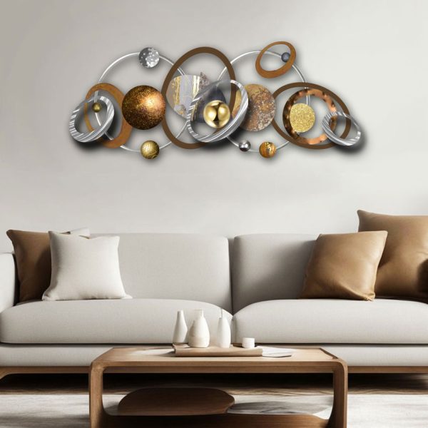 Orbit sculpture with metallic rings in silver, gold, and bronze tones, mounted above a cream-coloured contemporary sofa