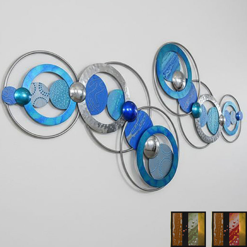 large-blue-abstract A modern abstract wall art piece composed of interconnected circular elements in various shades of blue, silver, and metallic, mounted on a plain white wall.