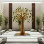Golden decorative tree sculpture in a modern indoor zen garden with bamboo plants and white stones.